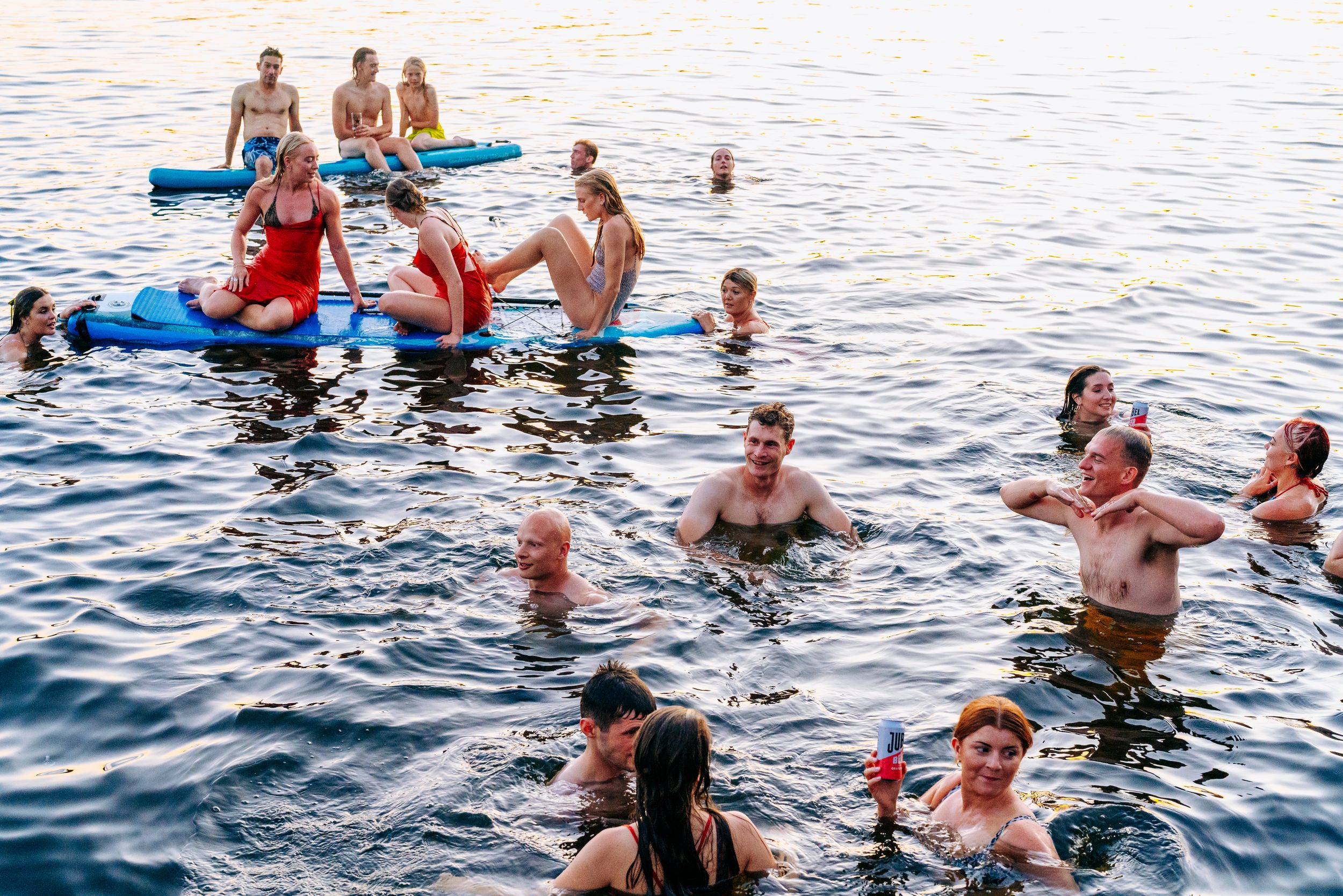 Wedding Party swimming and floating in a lake at golden hour sunset.