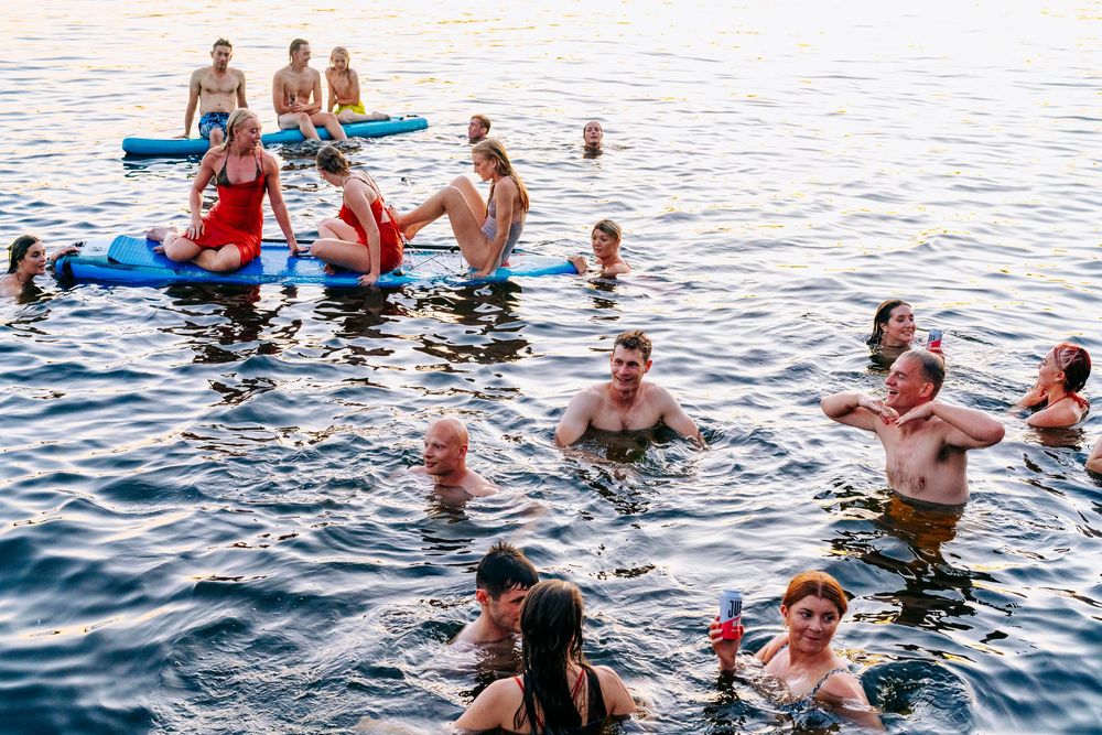 Wedding Party swimming and floating in a lake at golden hour sunset.