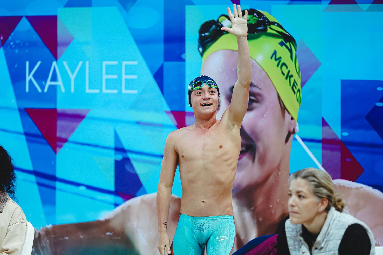 Competitive swimmer performs freestyle stroke during a race in blue swimming pool with lane markers.