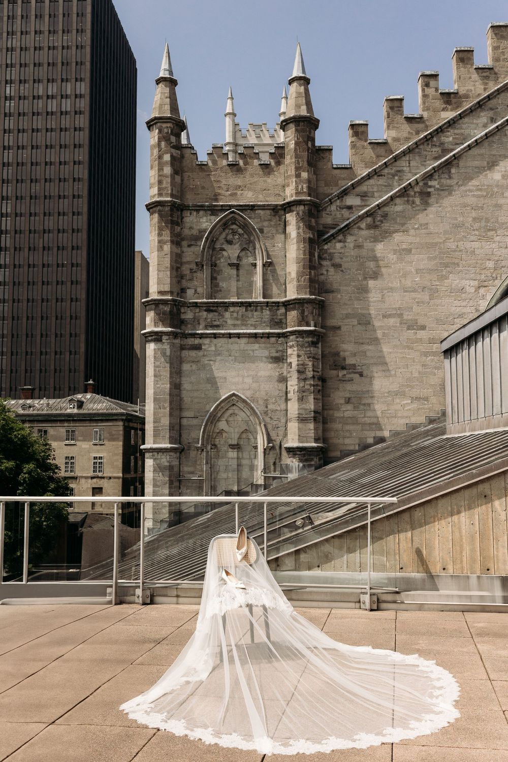 White wedding dress with long cathedral train photographed against gothic church architecture in urban setting.