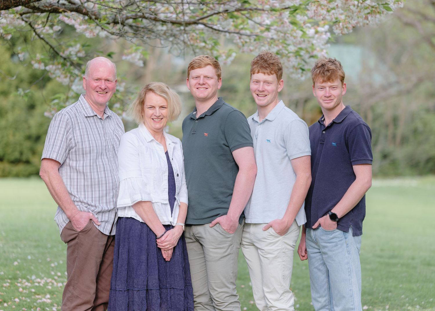 Group photo taken outdoors with blooming cherry trees in the background.