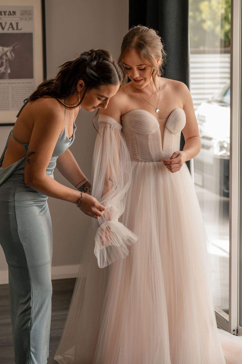Helper adjusts the tulle details on bride's dress during wedding preparations Cambridge New Zealand