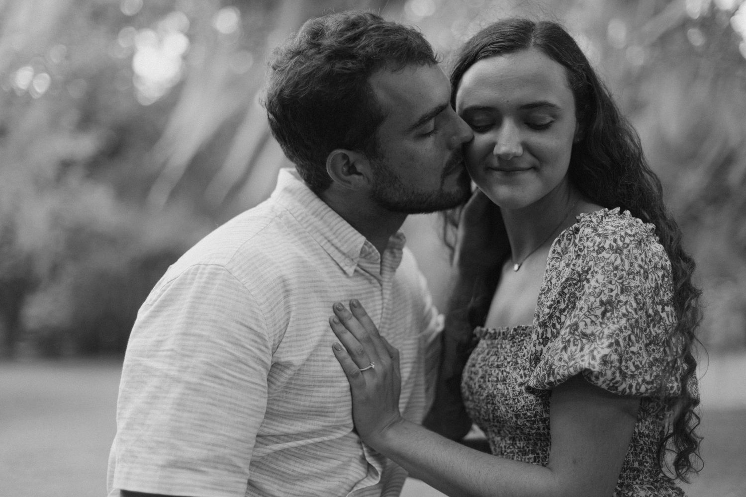 A tender moment captured in black and white between two people outdoors.