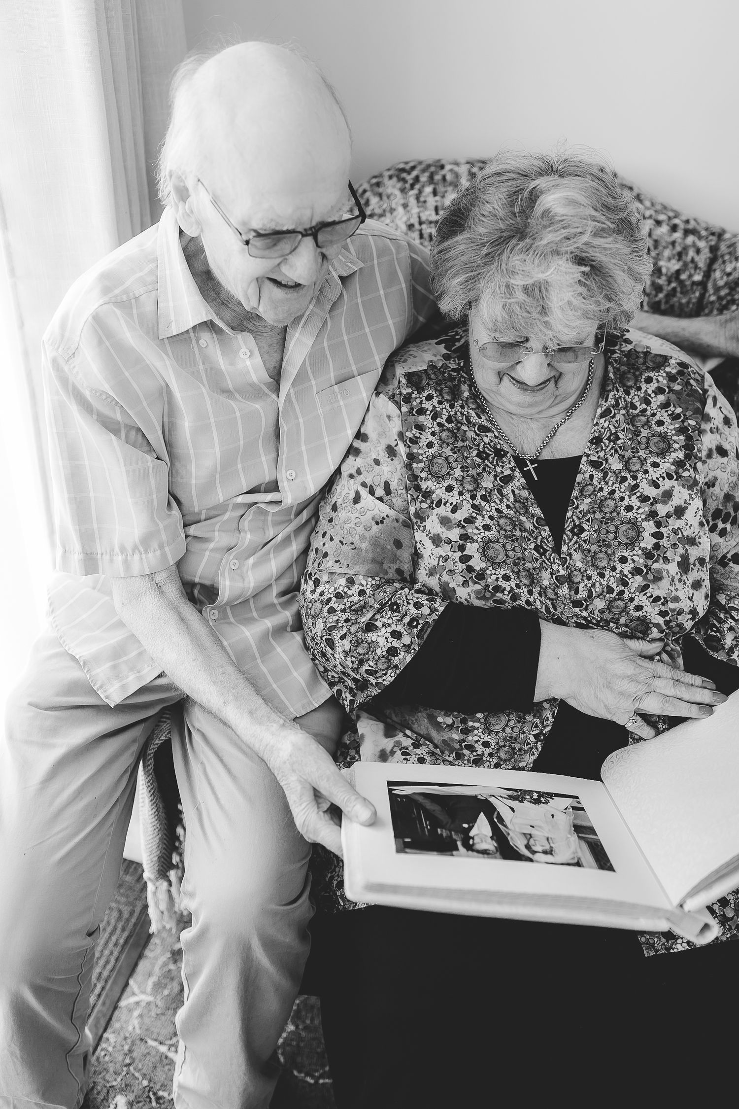 Elderly couple looking through a photo album together on couch. Photographer. Hull. East Yorkshire. Photography