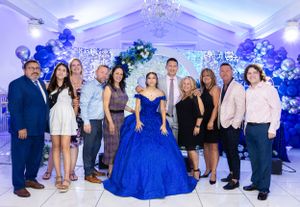 Group photo at an elegant event with blue decor and balloon arrangements.
