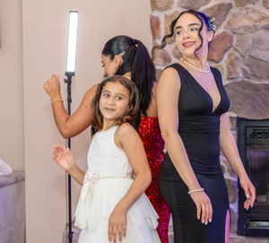 People posing with ring lights and photography equipment in front of a stone wall.