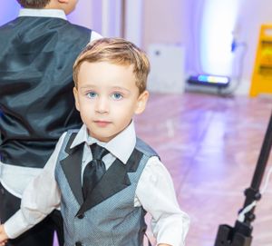 Young attendee in formal vest and tie at an indoor event.