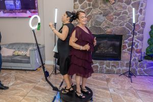 Two people using ring lights and photography equipment at an event with stone wall backdrop.