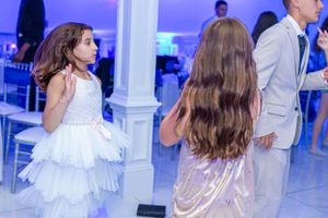 Elegant event space with white dress and formal attire visible among party guests.
