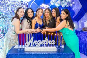 Group poses together by a blue-lit display with elegant decor and balloons.