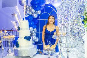 Elegant celebration features tiered white cake and blue balloon decor.