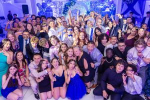 Crowded dance floor of celebration guests under blue lighting.