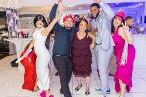Celebratory group pose with arms raised at formal event.