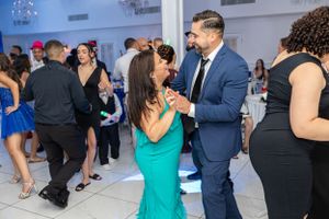 Guests dancing and socializing at formal event with elegant lighting.