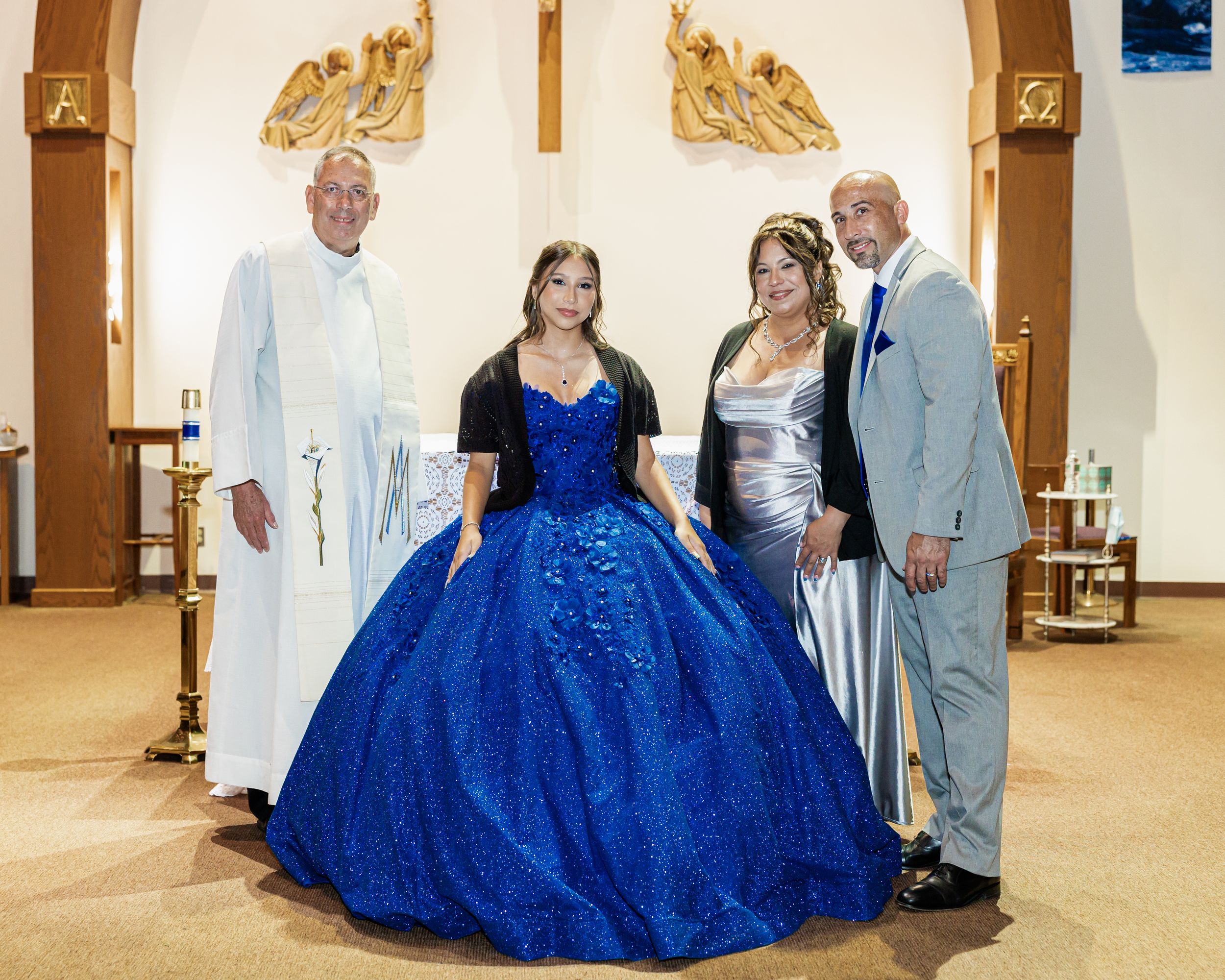 A formal group photo in a church with a spectacular royal blue quinceañera gown as the centerpiece.