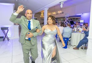 Wedding guests make a grand entrance at a reception venue with purple uplighting.