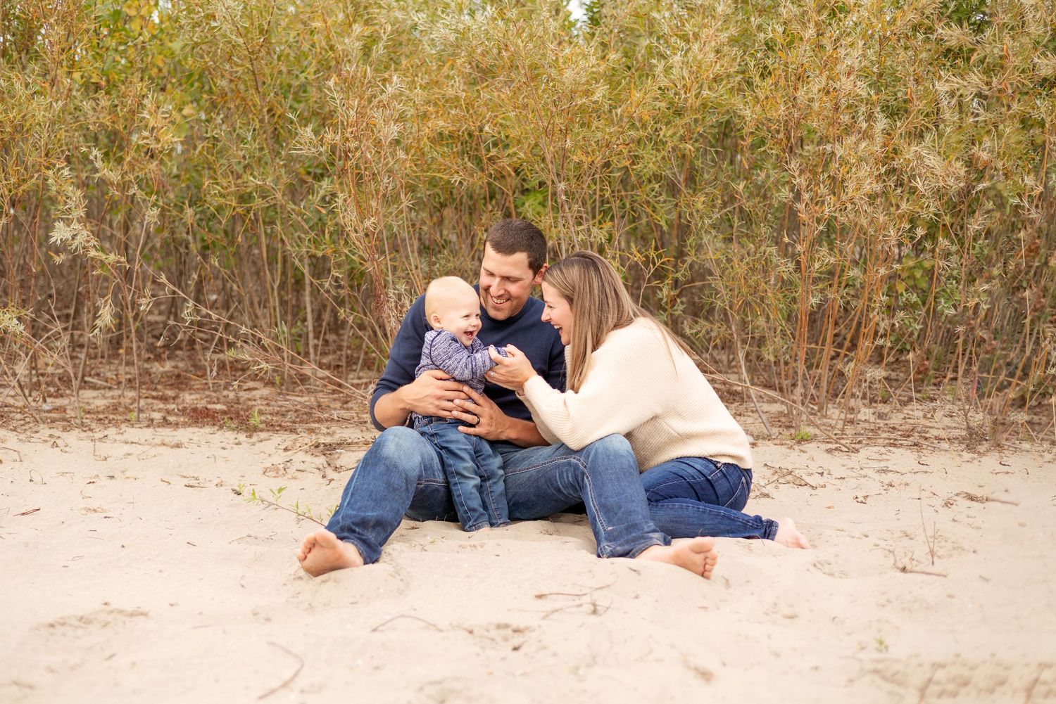 A family relaxes together on a sandy beach during a beautiful autumn photoshoot.