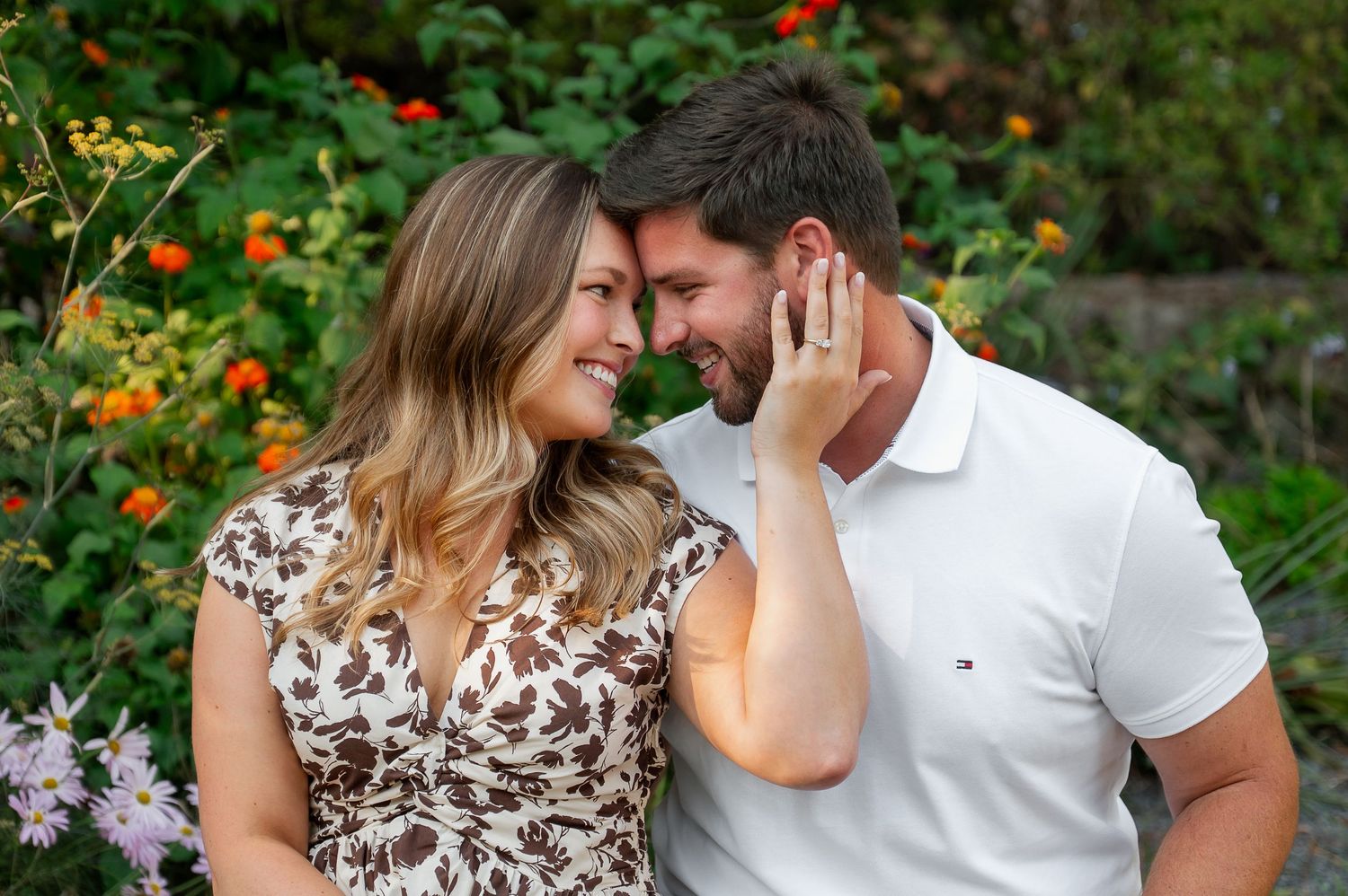 Intimate couple's portrait session among orange flowers in a lush garden.