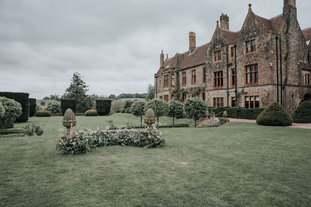 Exterior view of Huntsham Court wedding venue with sweeping lawns and garden floral styling in Devon
