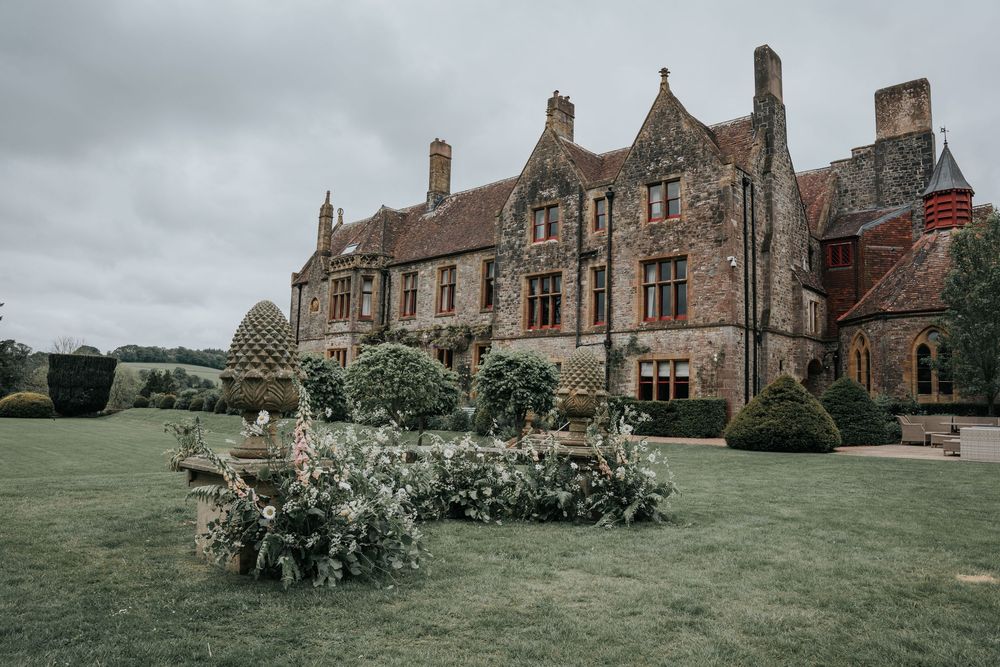 Exterior view of Huntsham Court wedding venue with sweeping lawns and garden floral styling in Devon
