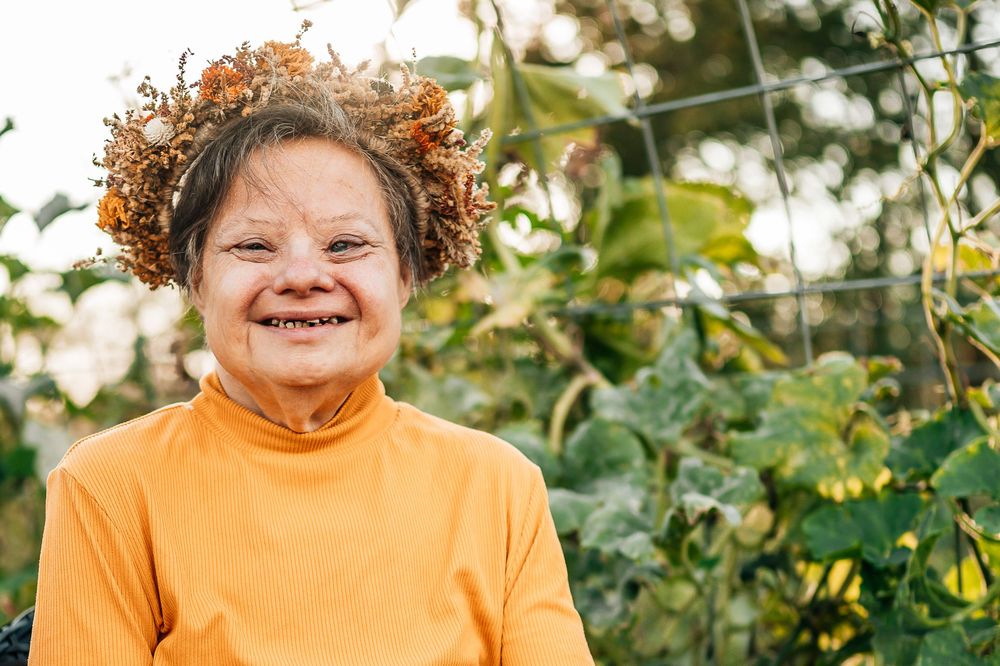 woman with down syndrome smiling big at the camera wearing a flower crown during an outdoor family photoshoot in north Richland hills Texas