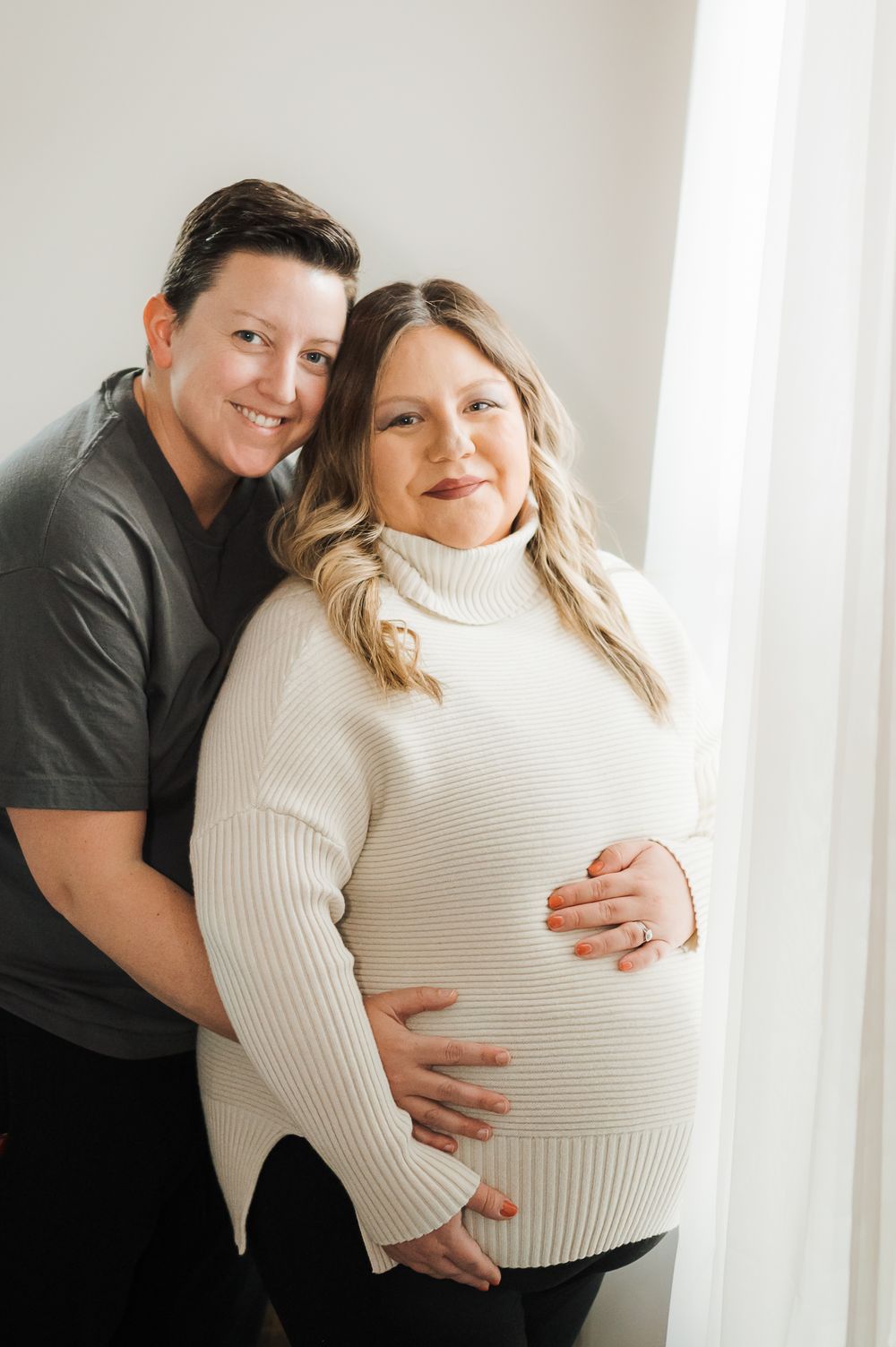 lesbian couple posing together smiling during an in home inclusive maternity photoshoot in colleyville Texas