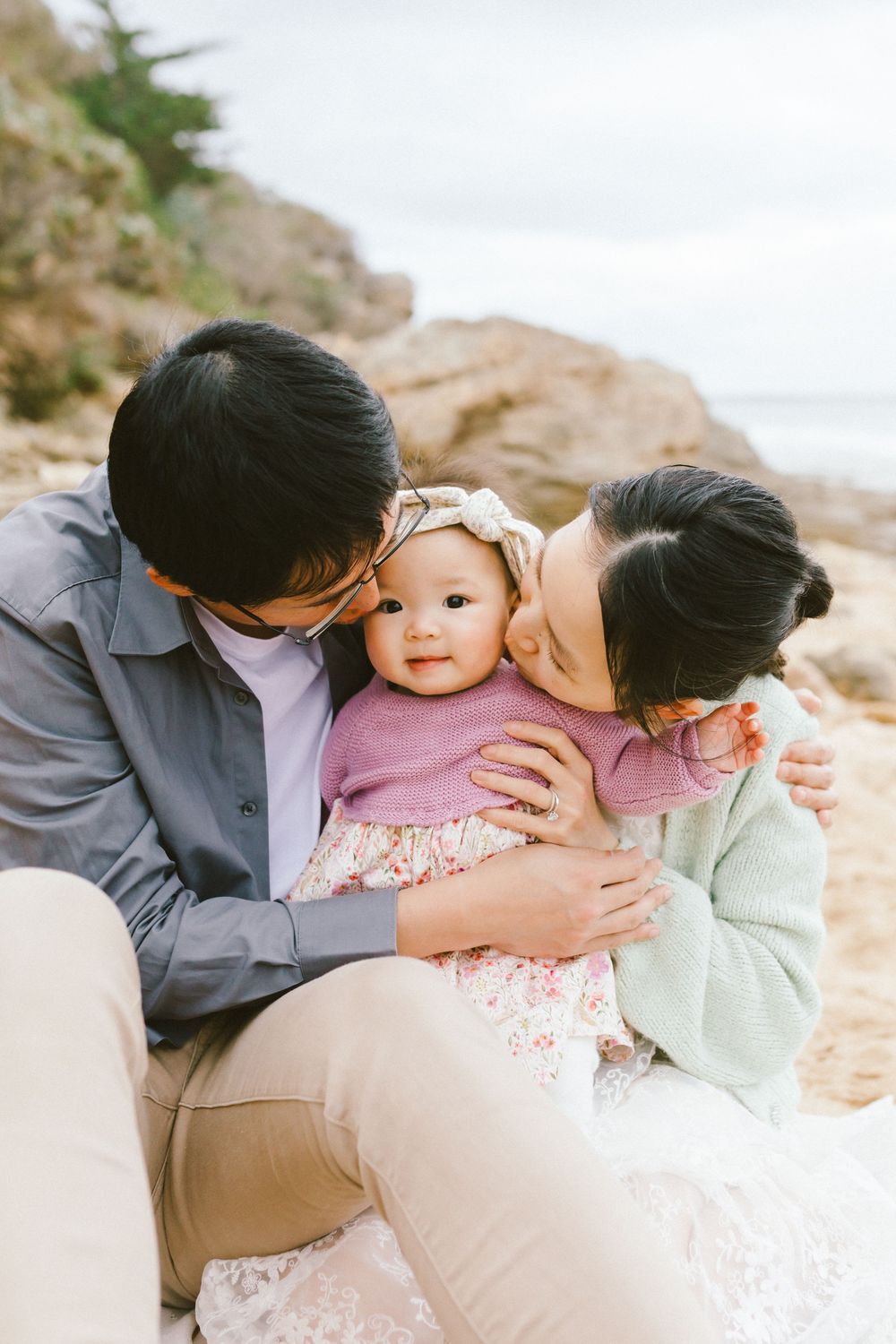 A tender family moment captured in a series of four intimate photos on a rocky beach setting.