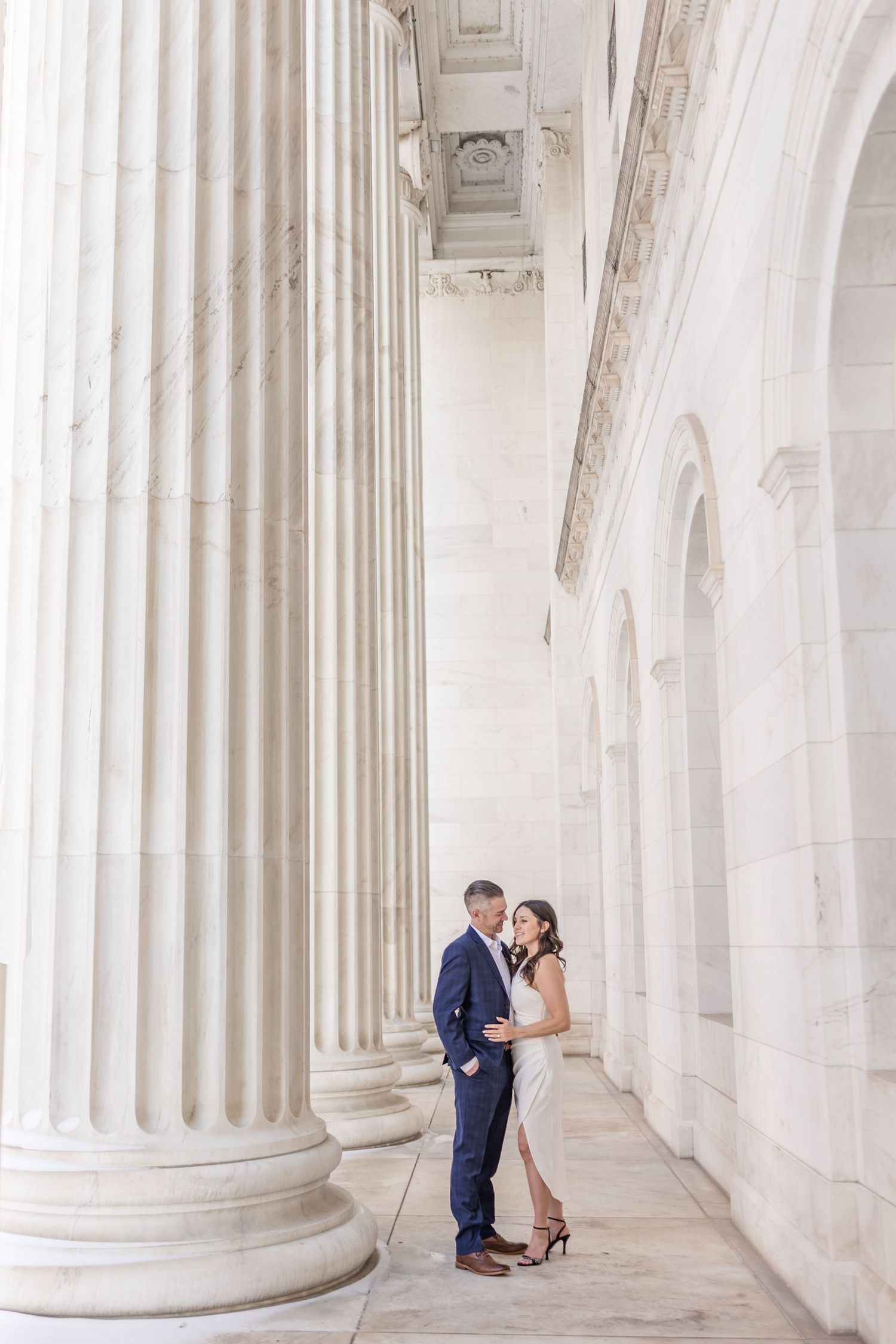 A romantic moment between a couple among elegant white marble columns.