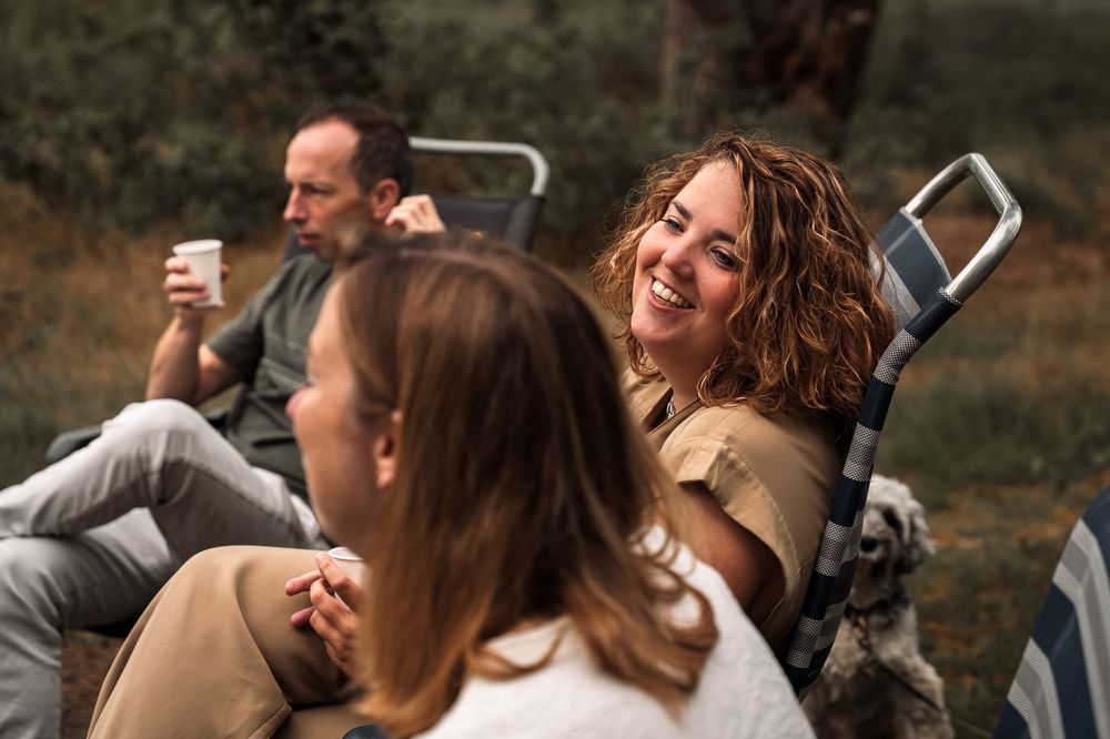 Wedding guests laugh and smile together during an outdoor celebration.