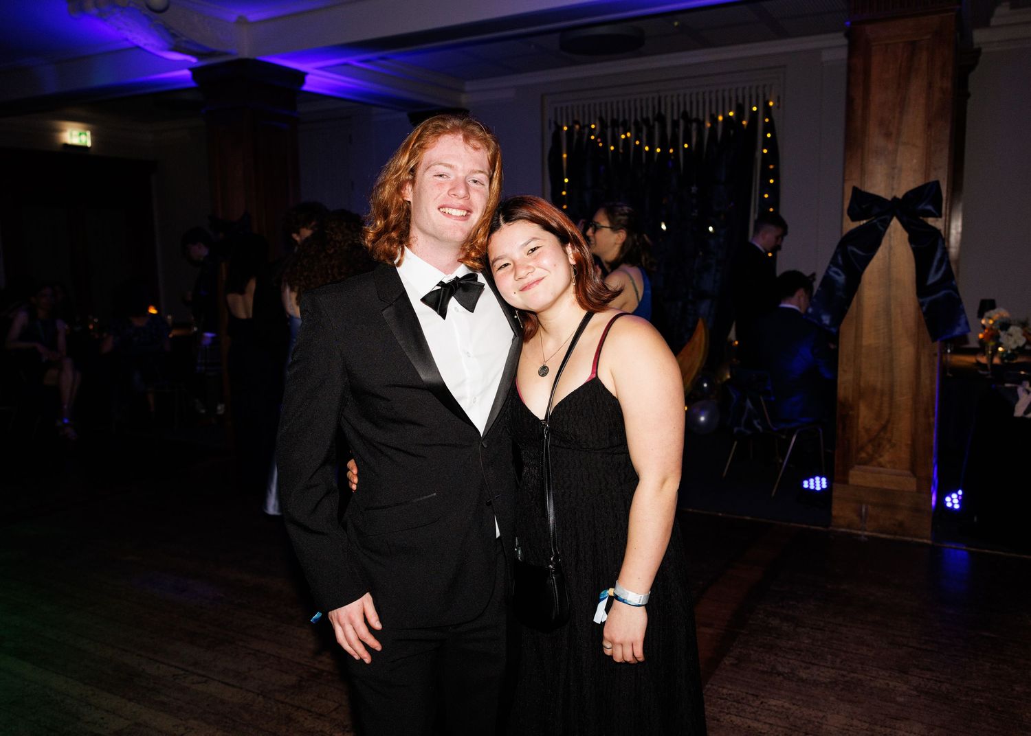 People dancing and socializing at a formal evening event with blue lighting in the background.