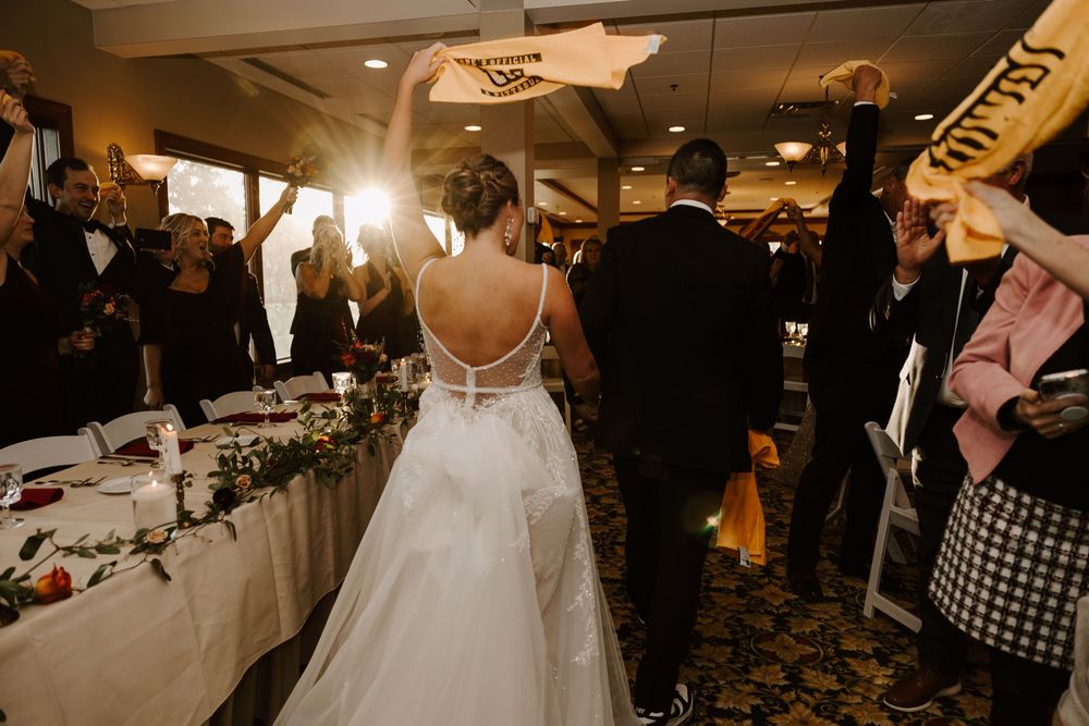 Wedding reception guests gather on a dimly lit dance floor during an evening celebration at an indoor venue.