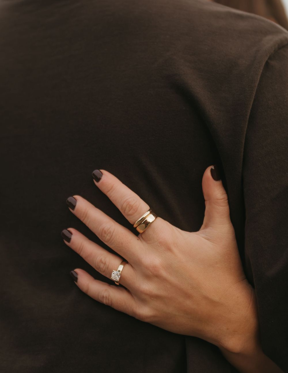 Close-up of hands embracing with an engagement ring visible.