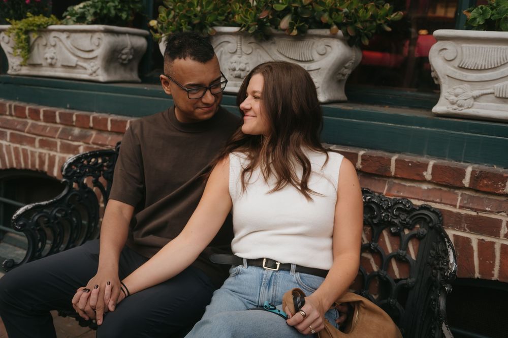 A couple shares an intimate moment while sitting together on outdoor brick steps.