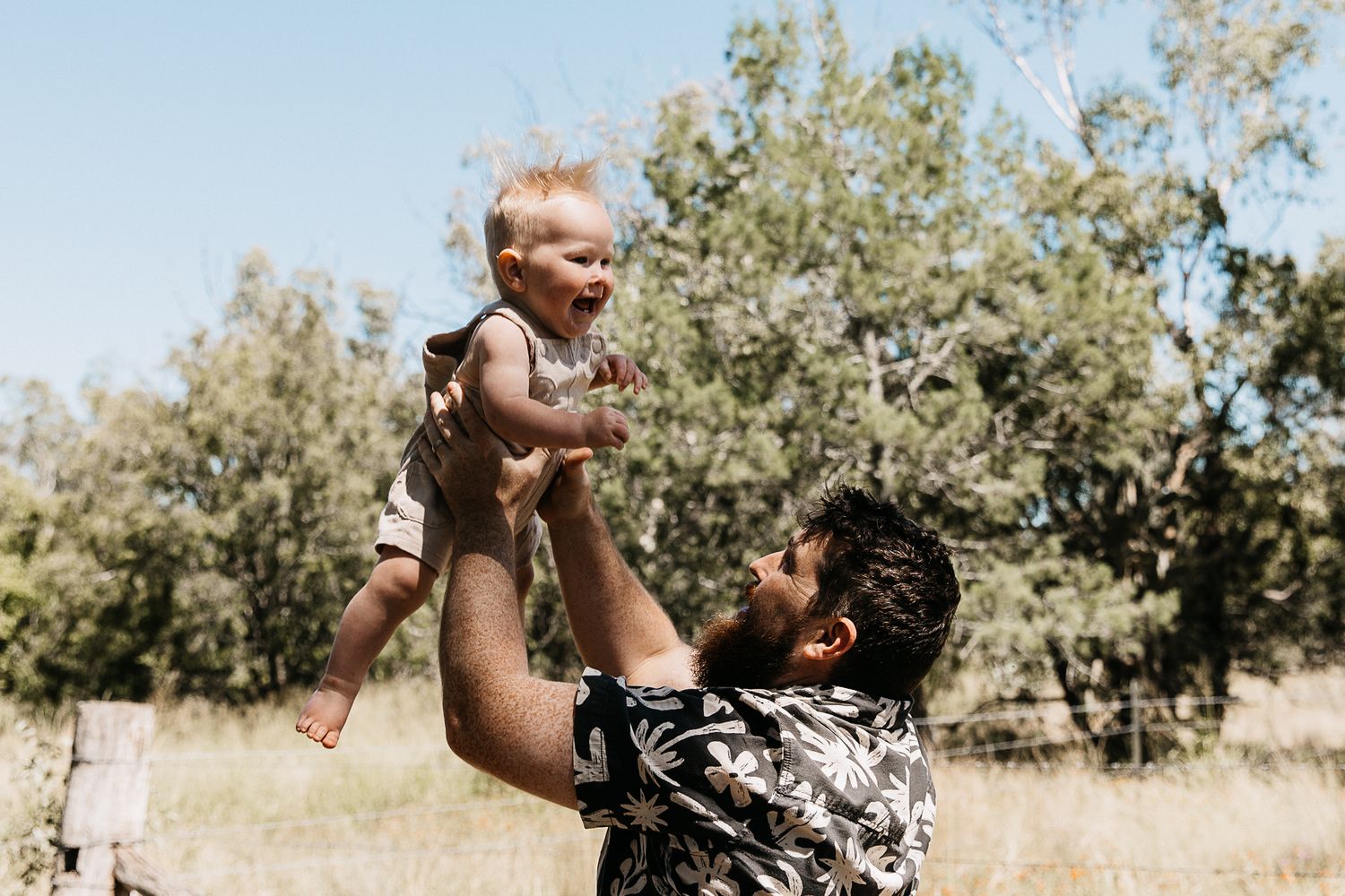 Little boy being thrown in the air by his dad  during a professional cake smash photo shoot.