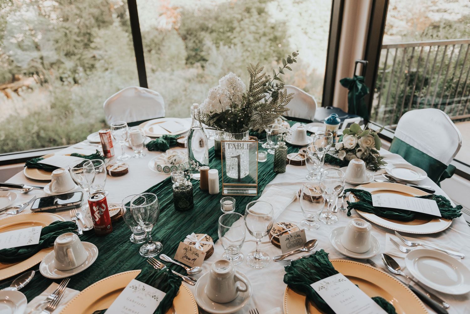 Elegant table settings with white plates and gold accents in a modern restaurant interior with natural lighting.