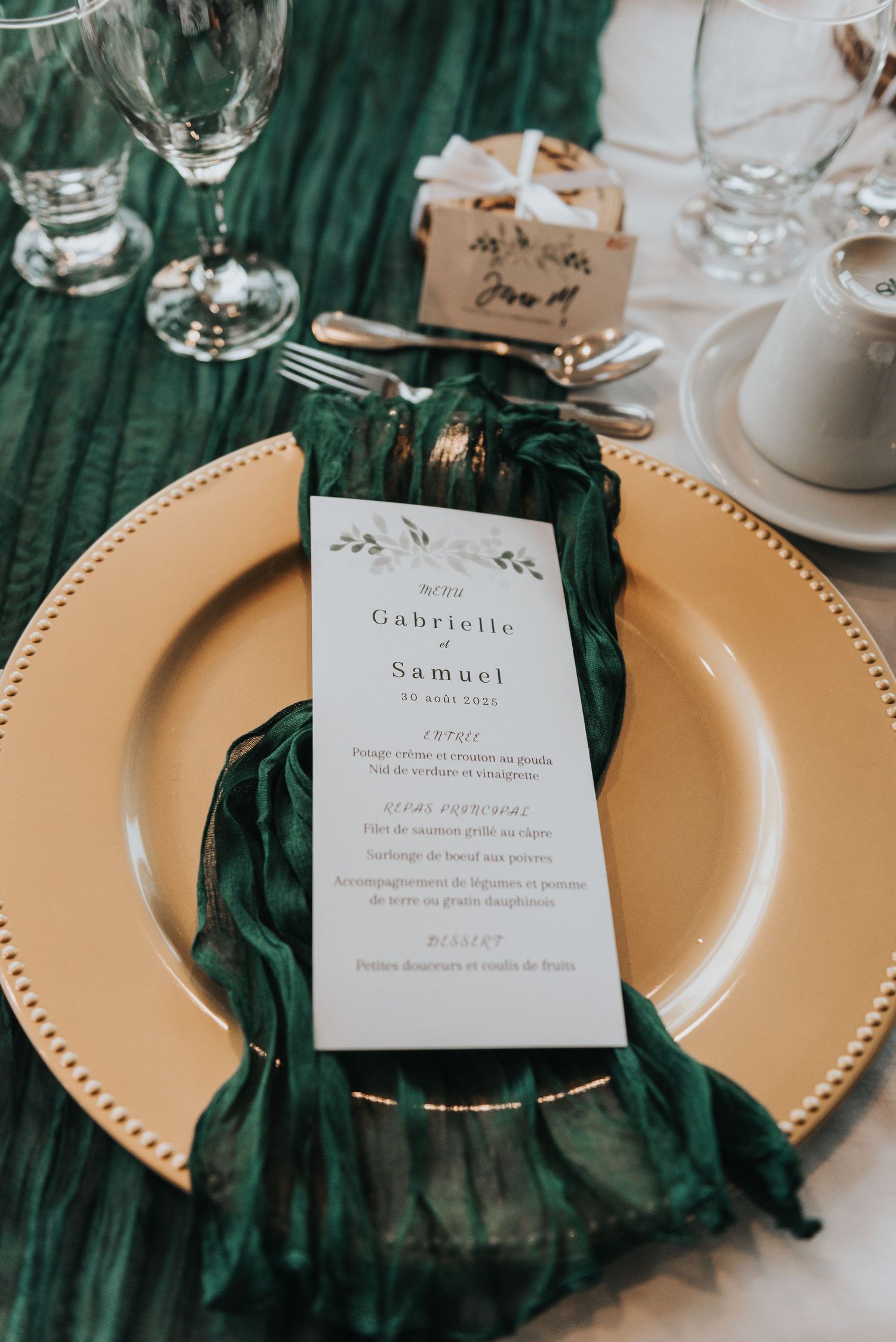 Elegant wedding place setting with emerald green napkin, gold charger plate and menu card for Gabrielle and Samuel.