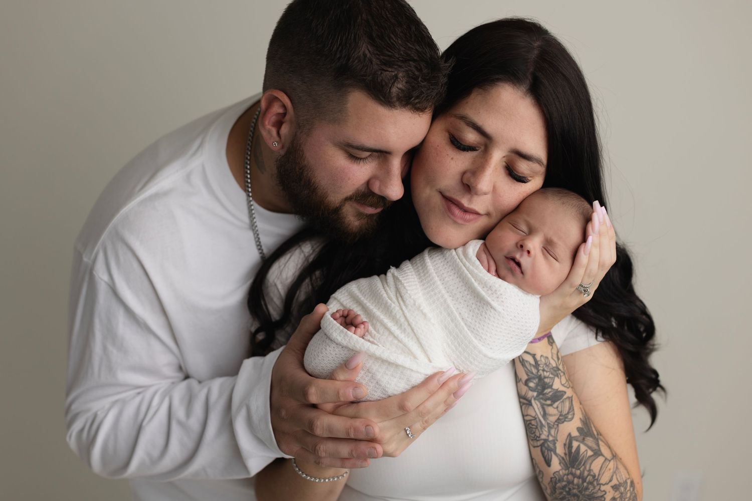 A tender moment between parents and their newborn baby captured in black and white photography.