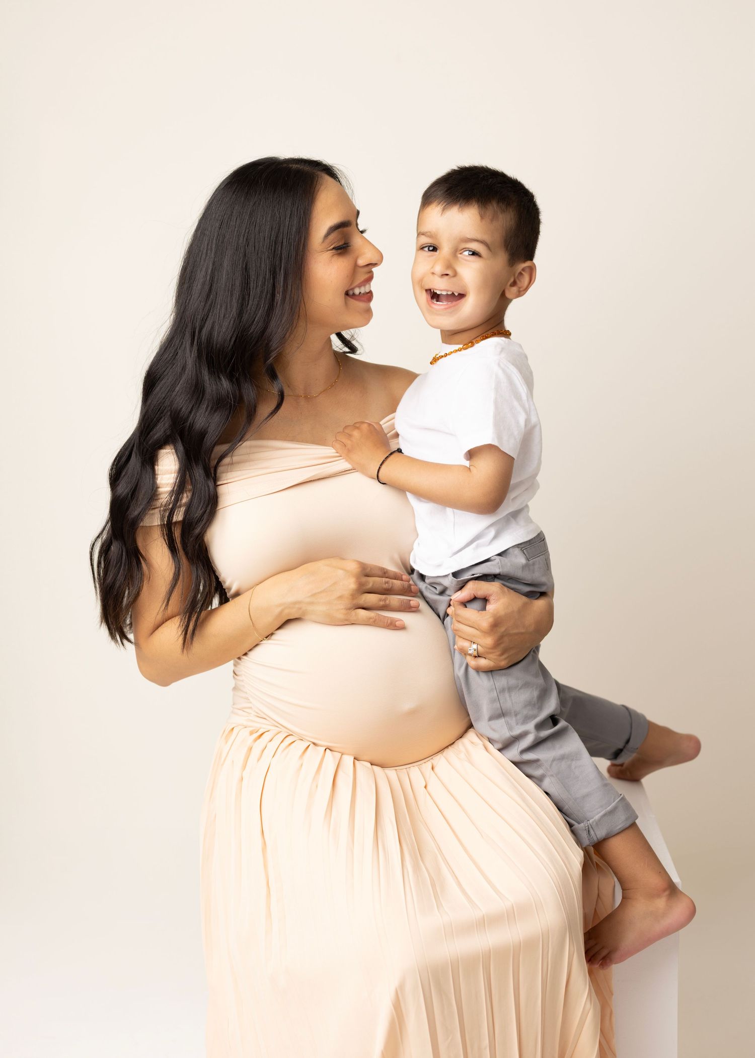 A mother in a peach dress shares joyful moments with her toddler in a series of candid photos.