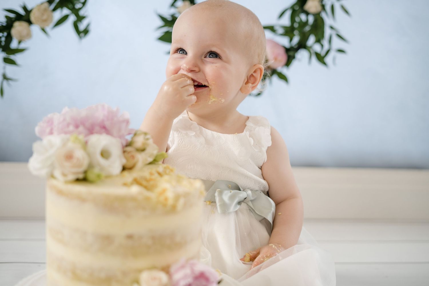 Natural family photography of a baby sitting with a first birthday cake during a relaxed lifestyle family photoshoot