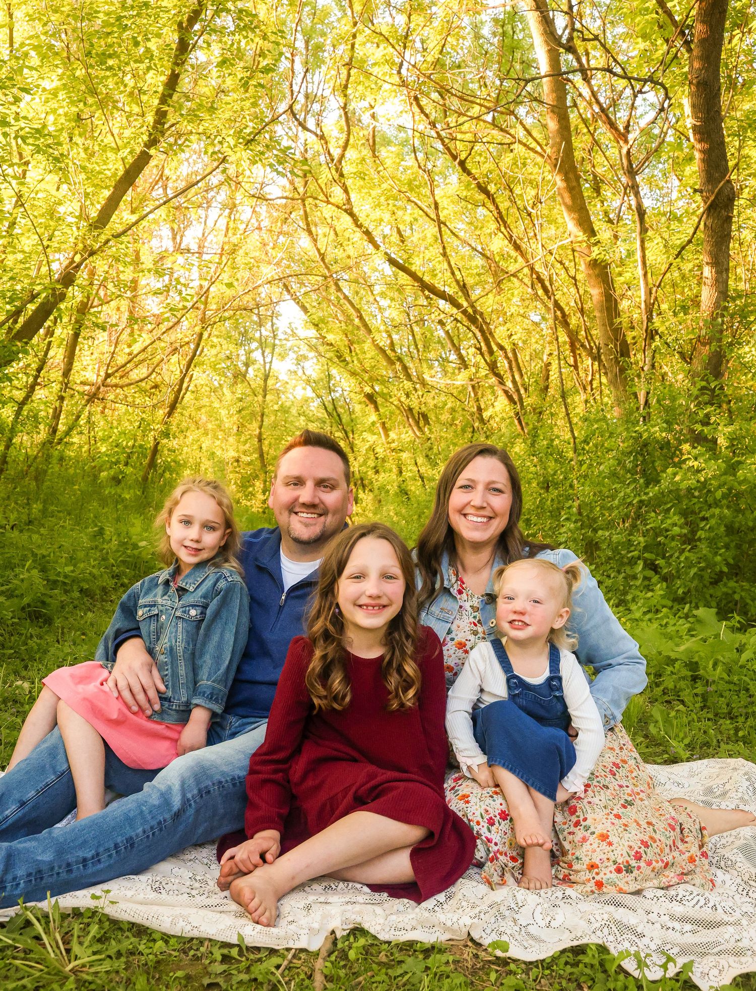 Spring family photos of family sitting on a blanket in the forest.