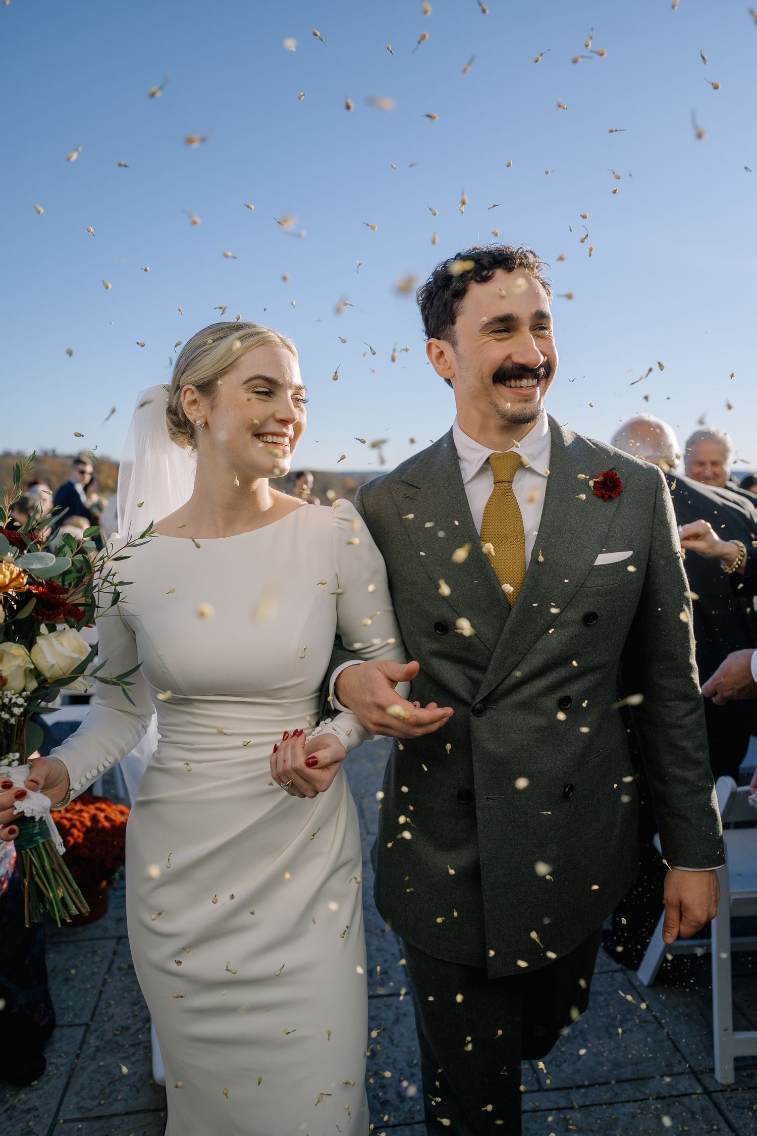 A flowing white wedding veil catches the breeze on a golf course during an autumn day with golden trees.