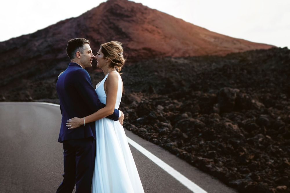 Newlyweds sharing an intimate moment on a road through the Timanfaya volcanic landscape - Epic Lanzarote wedding