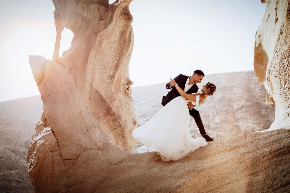 Groom dipping the bride for a kiss inside the dramatic rock formations of Las Peñitas - Epic wedding portraits by photoFuerte