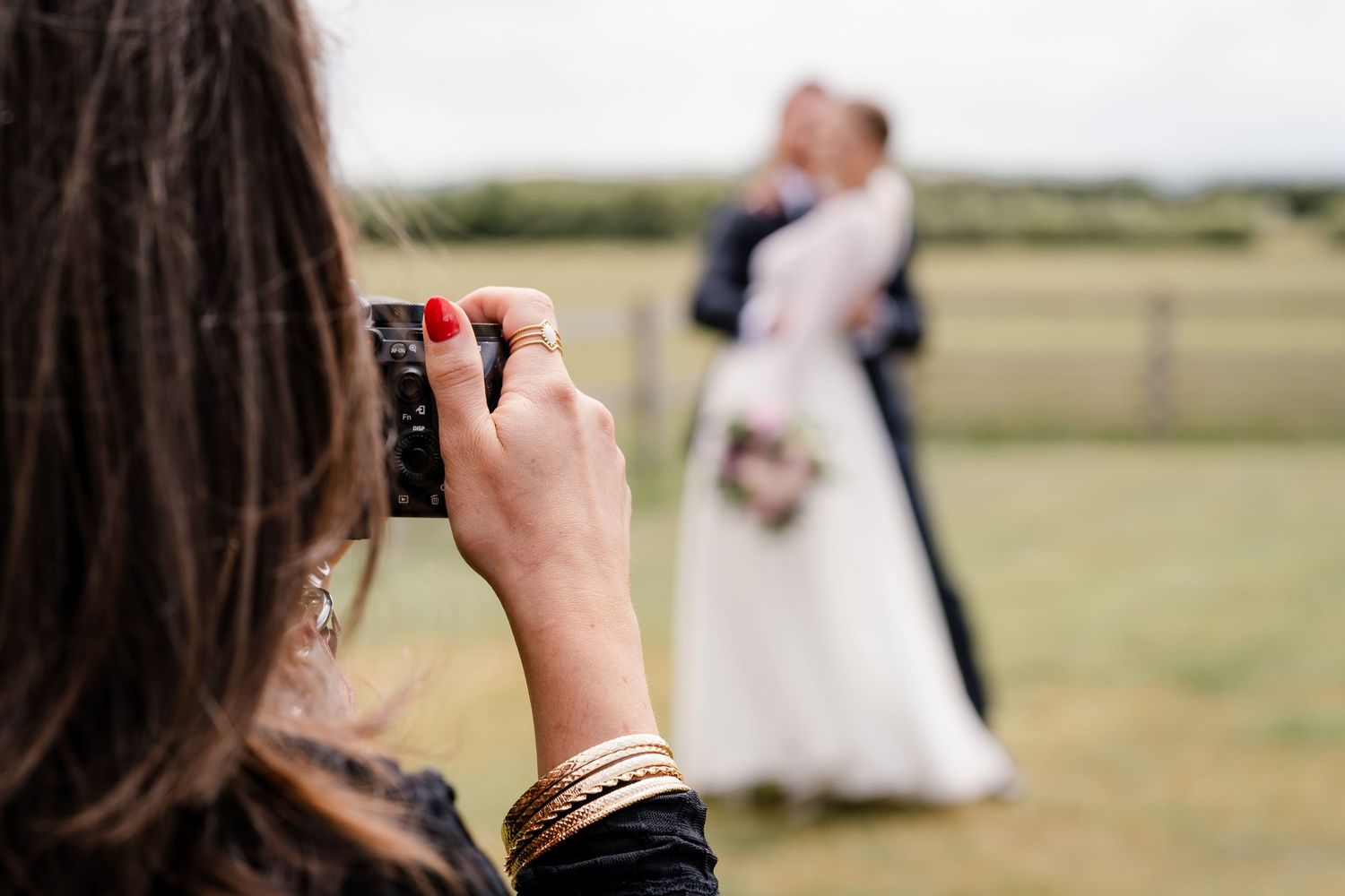 Black and white photo of photographer taking wedding photos in a garden setting.