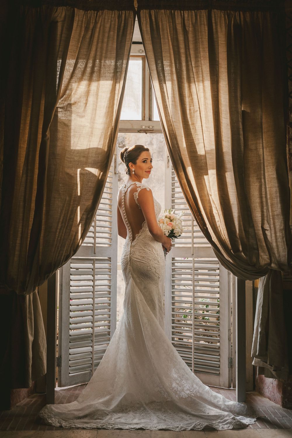 Bride stands in the frame of a traditional balcony door in Cartagena.