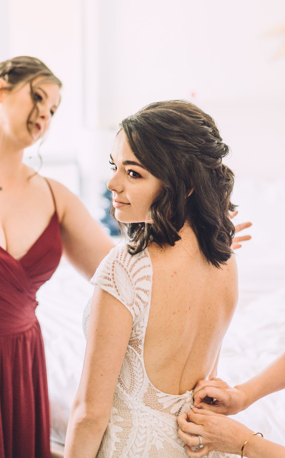 Close-up of an elegant backless lace wedding dress being adjusted.