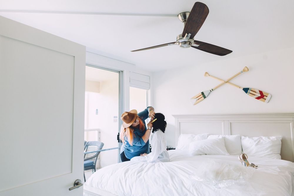 Two people jumping playfully on a white bed in a bright modern bedroom.