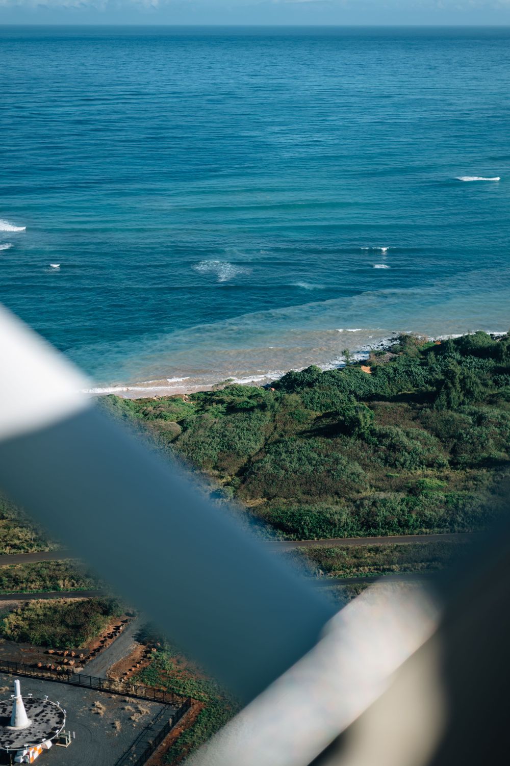 Bird's eye perspective of a tropical coastline with runway visible near water.