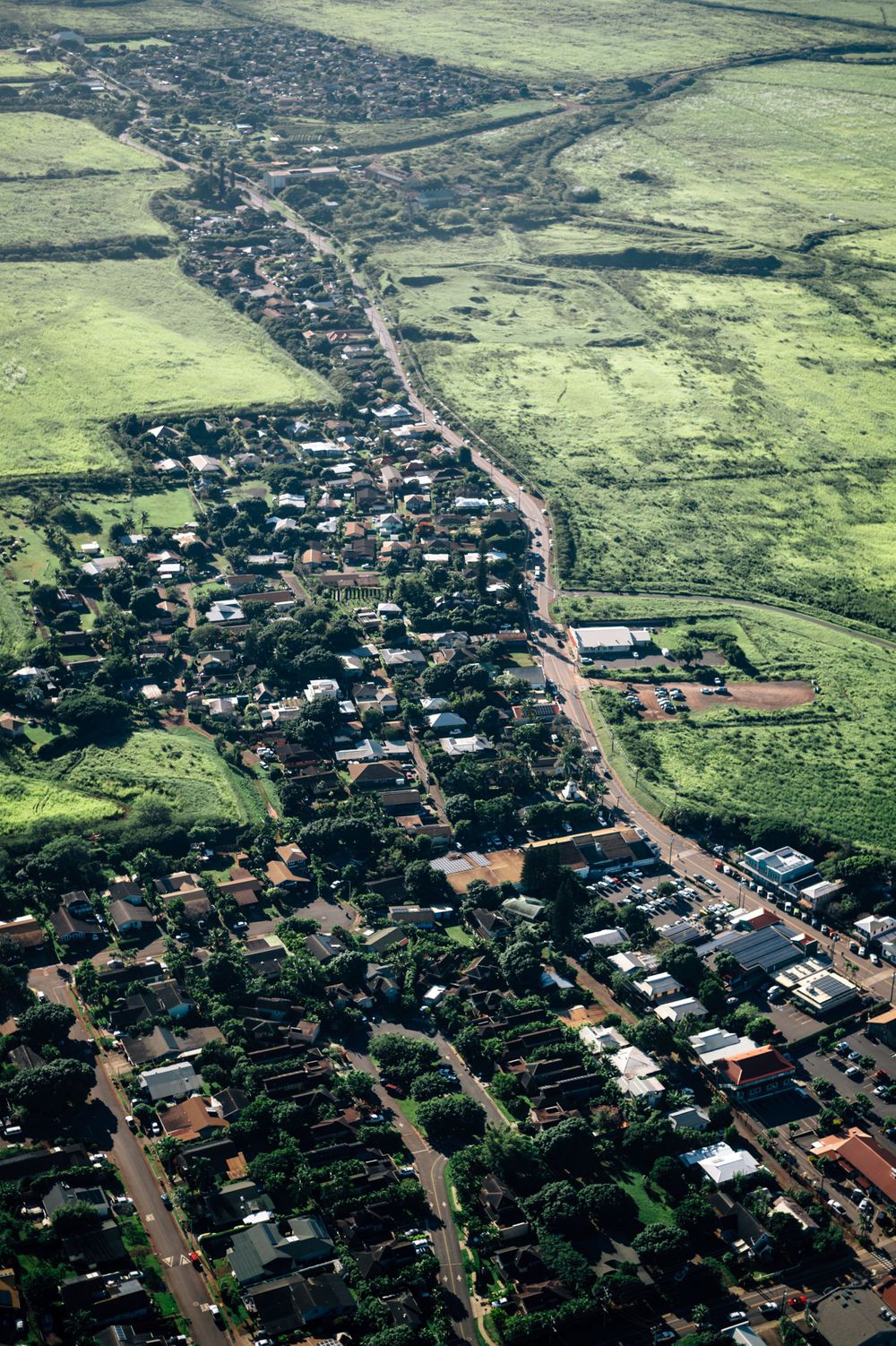 Aerial view of a small town nestled in green countryside with roads winding through residential areas.