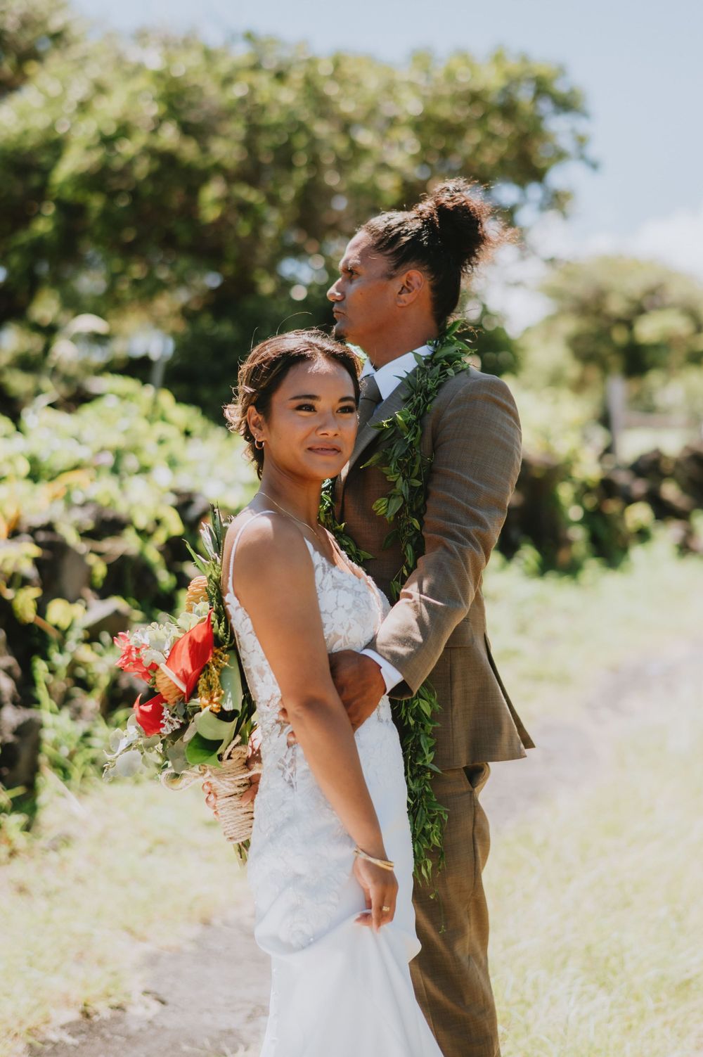 Couple sharing playful moment during outdoor wedding photoshoot in natural setting.